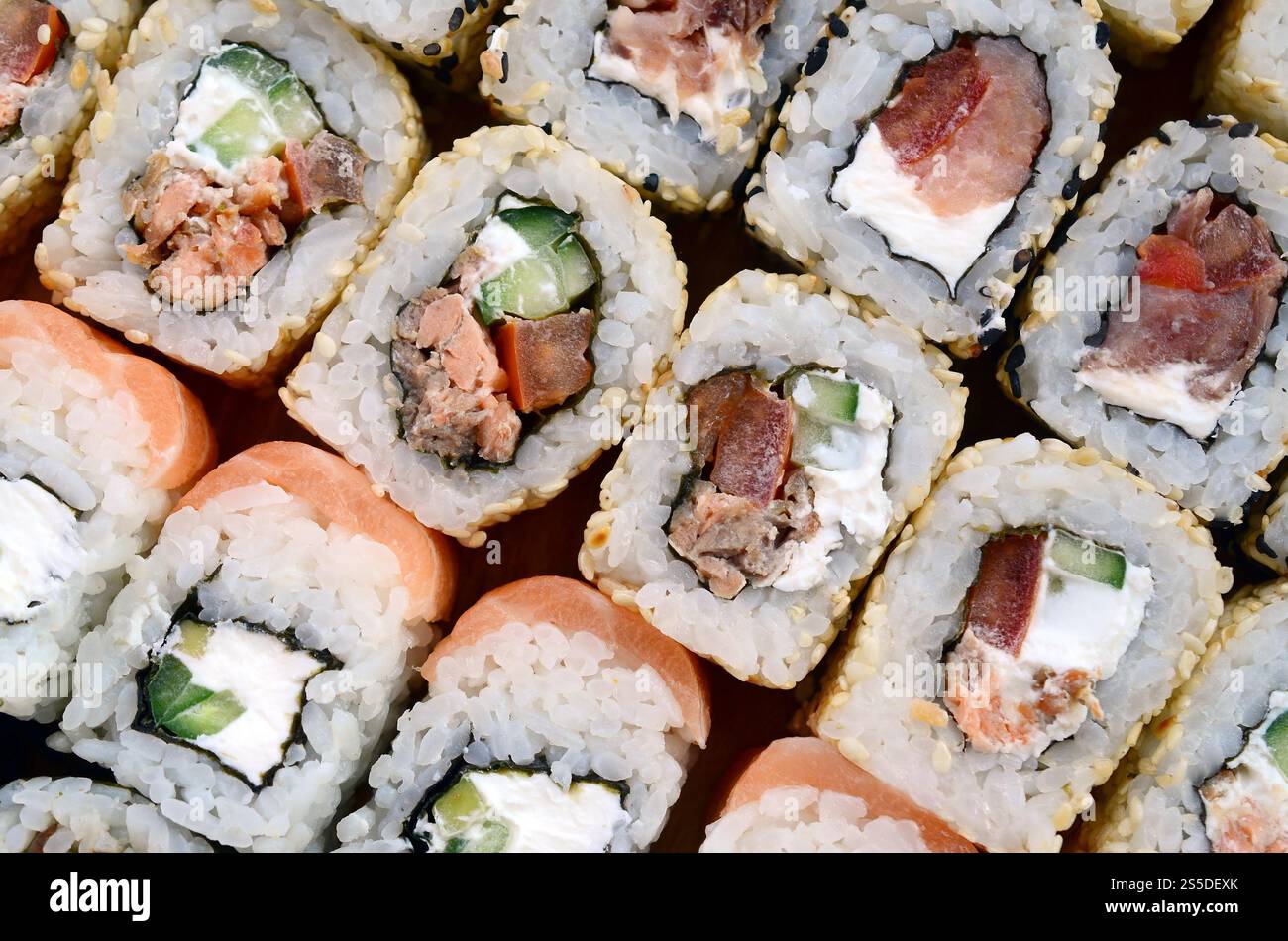 Primo piano di un sacco di sushi roll con diversi ripieni. Macrofo di cucina classica giapponese cotta. Immagine di sfondo Foto Stock