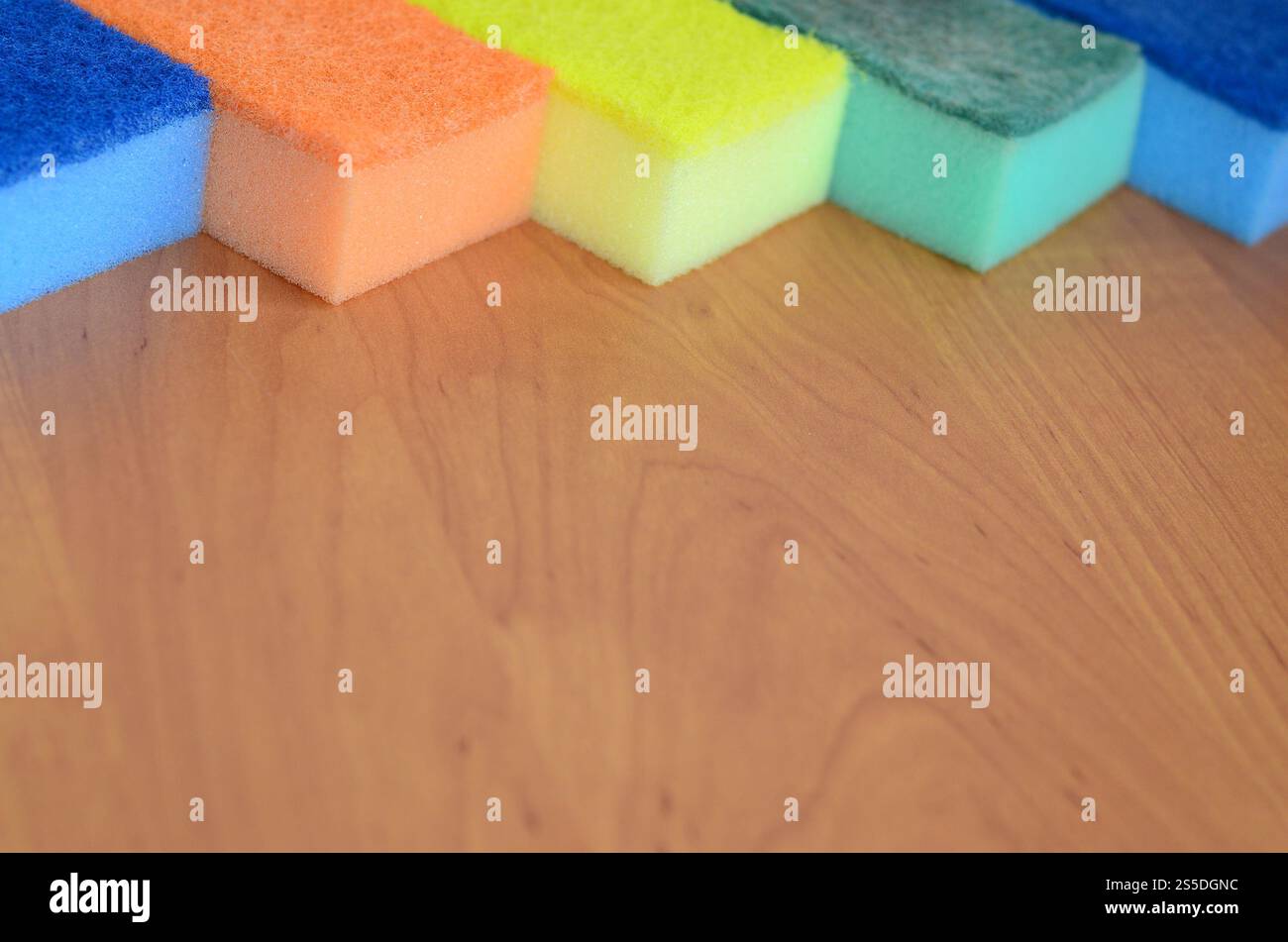 Un paio di spugne cucina giacciono su una cucina in legno il ripiano del bancone. Gli oggetti colorati per il lavaggio di stoviglie e pulizia in casa sono pronto per l'uso Foto Stock
