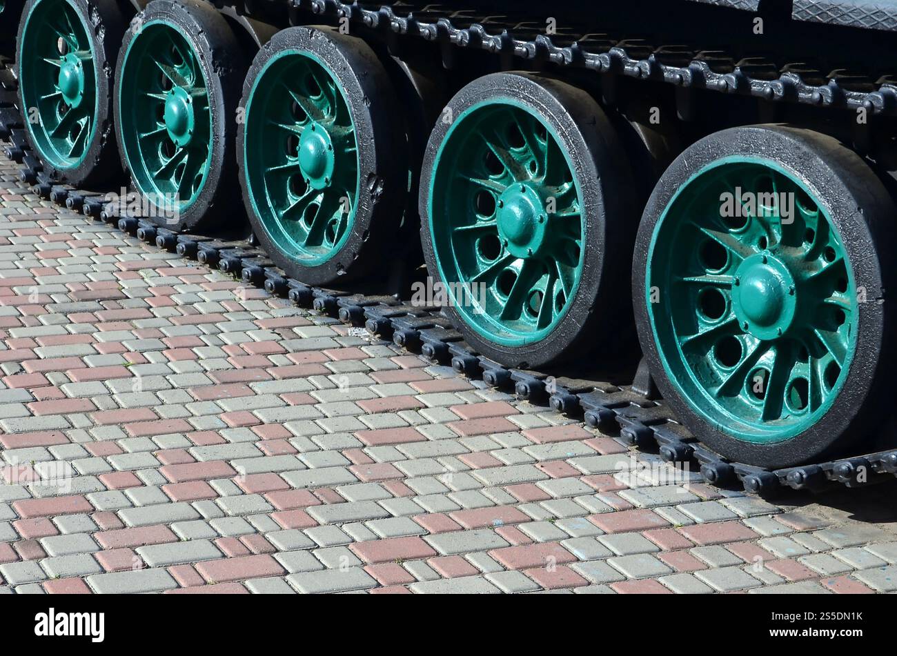 Un veicolo militare su cingoli sorge su un quadrato di pietre per pavimentazione. Foto di bruchi verde con ruote metalliche che li ruotano Foto Stock