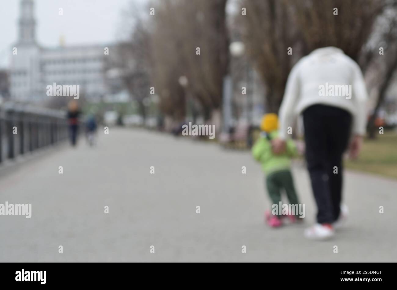 Paesaggio sfocato del parco primaverile vicino al lungomare. Strada davanti, decorata con alberi e una bassa recinzione dell'argine. Paesaggio sfocato di Foto Stock