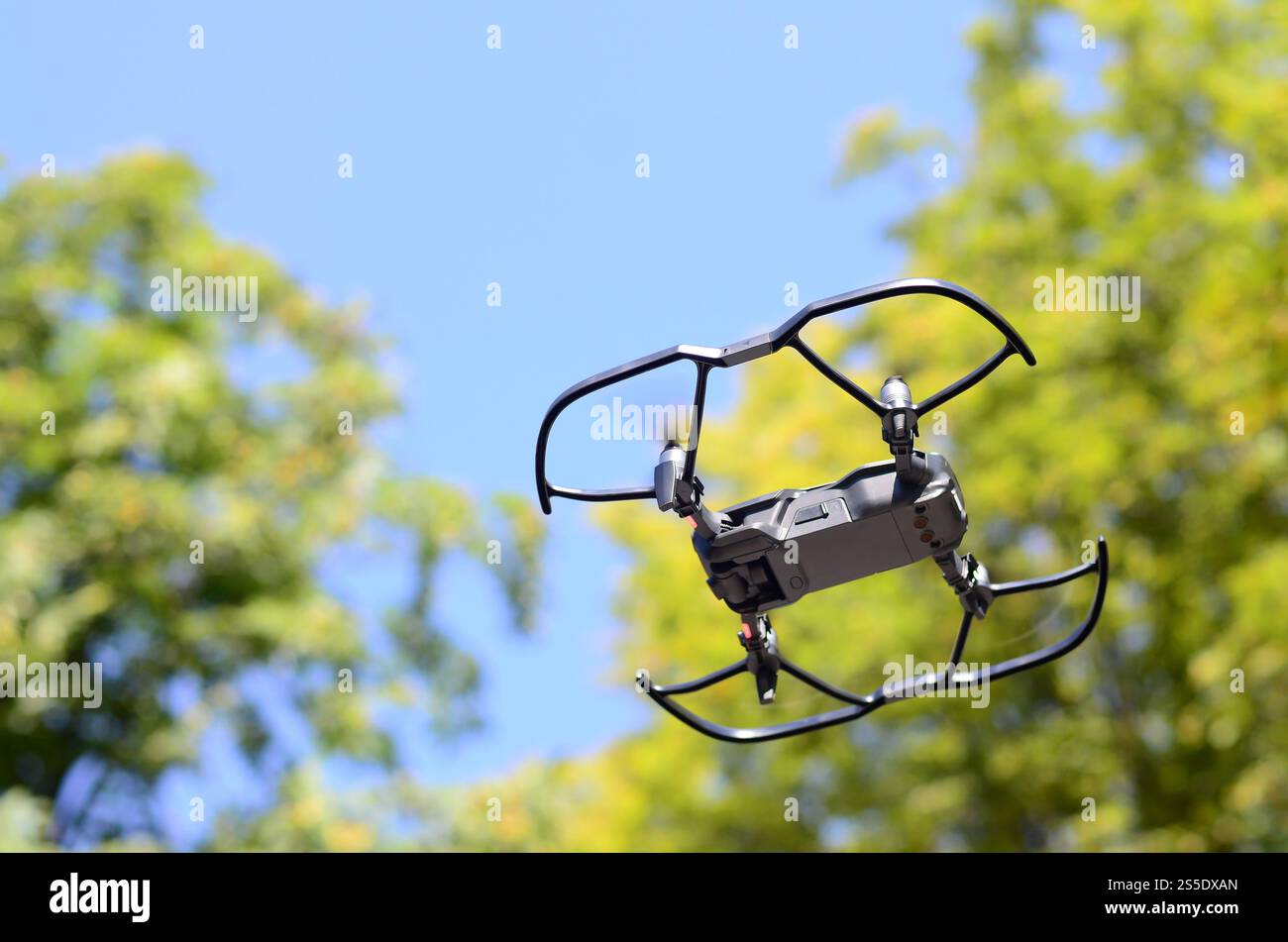 Drone con fotocamera decolla dalla terraferma e vola per scattare foto aeree al tramonto davanti agli alberi. Drone con fotocamera decollo da Foto Stock