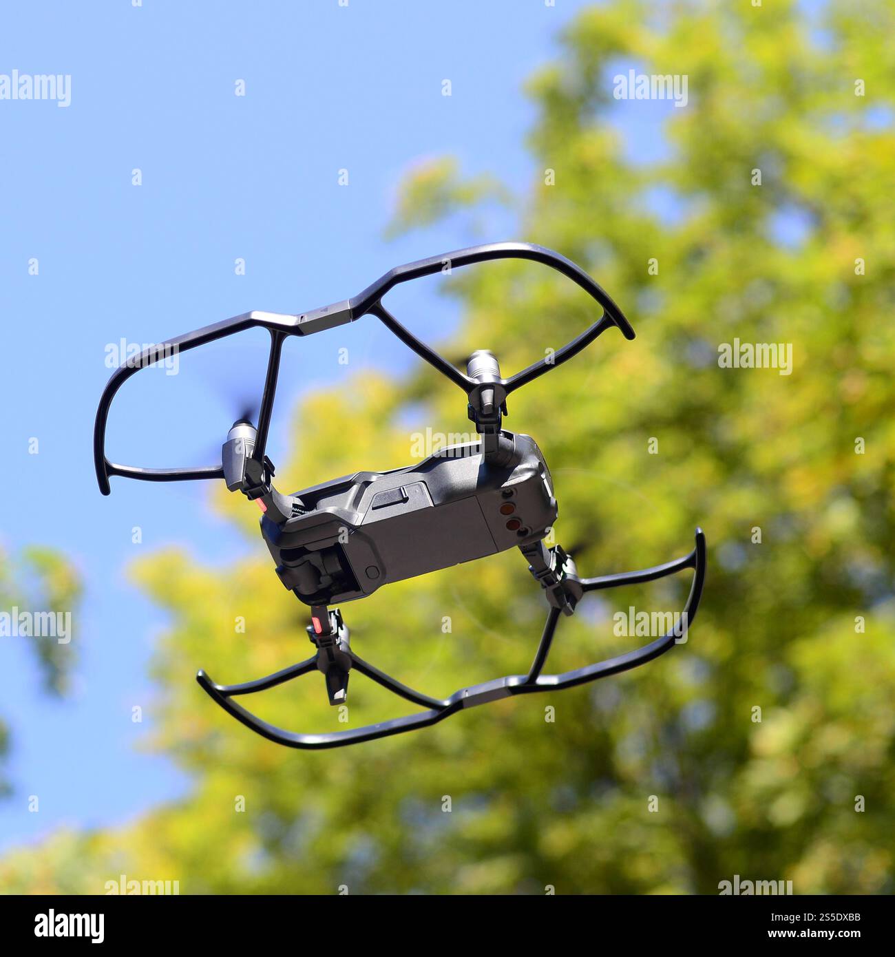 Drone con fotocamera decolla dalla terraferma e vola per scattare foto aeree al tramonto davanti agli alberi. Drone con fotocamera decollo da Foto Stock