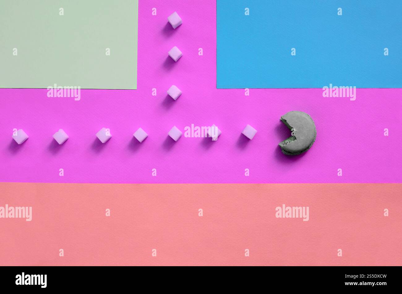 Una composizione di macaroon a bocca aperta che mangia cubetti di zucchero su sfondo rosa, lime, blu e corallo pastello. Il concetto di vecchio Foto Stock