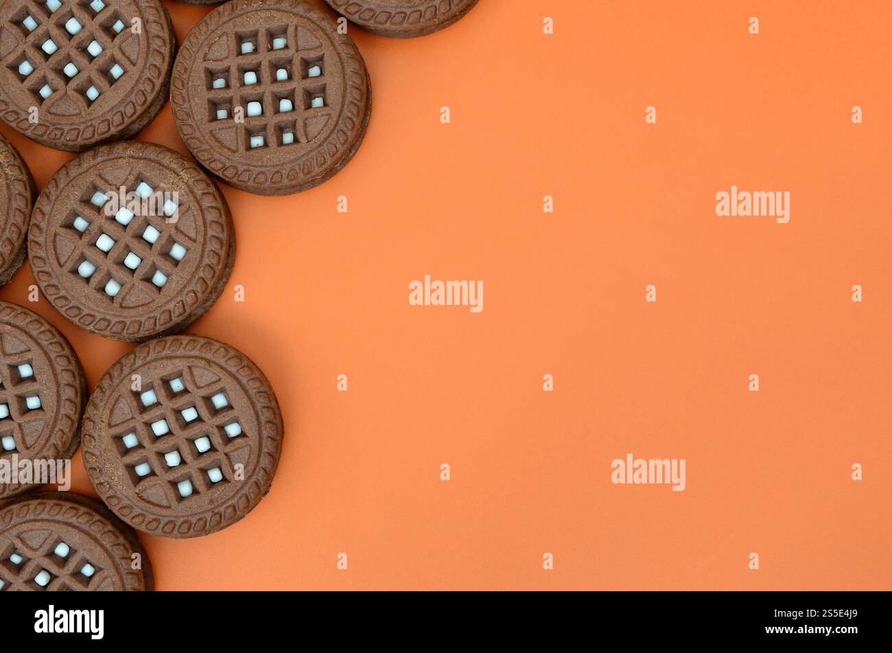 Immagine dettagliata di color marrone scuro round cookie sandwich con noce di cocco ripieno su una superficie di colore arancione. Immagine di sfondo di un close-up di diverse chicche per Foto Stock