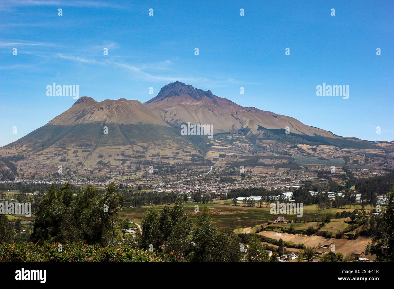 Il maestoso vulcano Imbabura in Ecuador, circondato da un mosaico di terreni agricoli e da una vibrante campagna sotto un cielo azzurro. Foto Stock