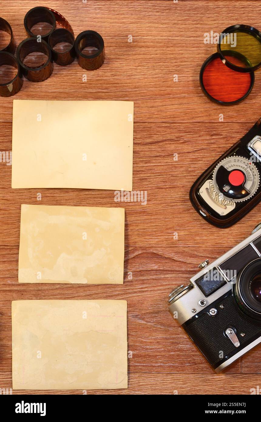 Fotocamera d'epoca, accessori fotografici e cornici vuote su un tavolo in legno. Natura morta con spazio di copia. Vista dall'alto. Immagine dai toni retrò in beige Foto Stock