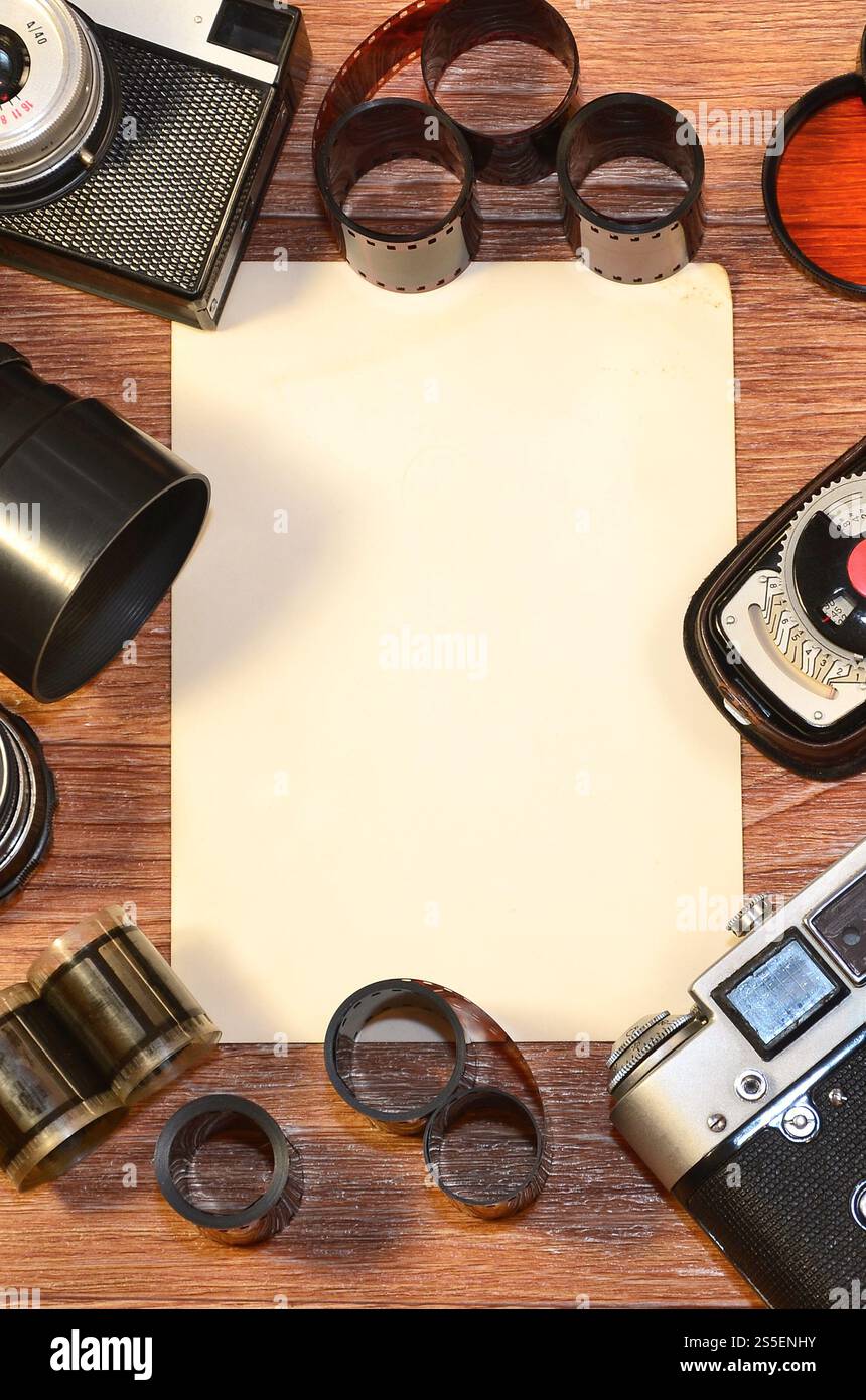Macchina fotografica retrò e alcune vecchie foto su un tavolo di legno. Mock up vintage per la presentazione di disegni o logo con fotocamera e obiettivo. Vista dall'alto. Foto Stock