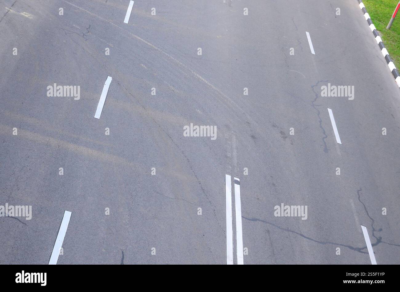 Strada asfaltata danneggiata con buche. Riparazione patch dell'asfalto. Asfalto cattivo pericoloso strada di automobili rotta, crepe e buche nell'asfalto. Foto Stock