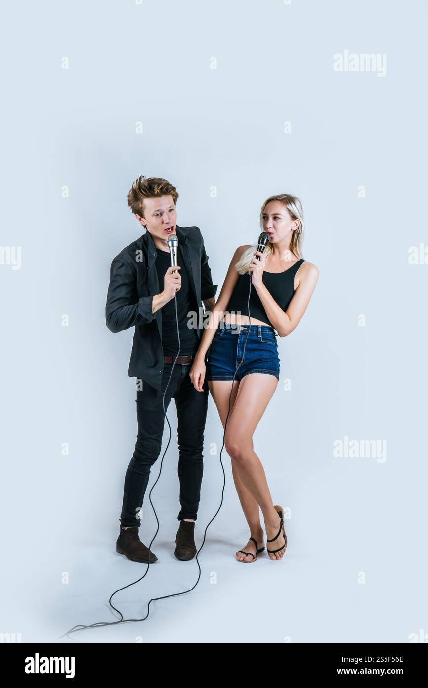 Felice ritratto di coppia tenendo il microfono e cantando una canzone Foto Stock