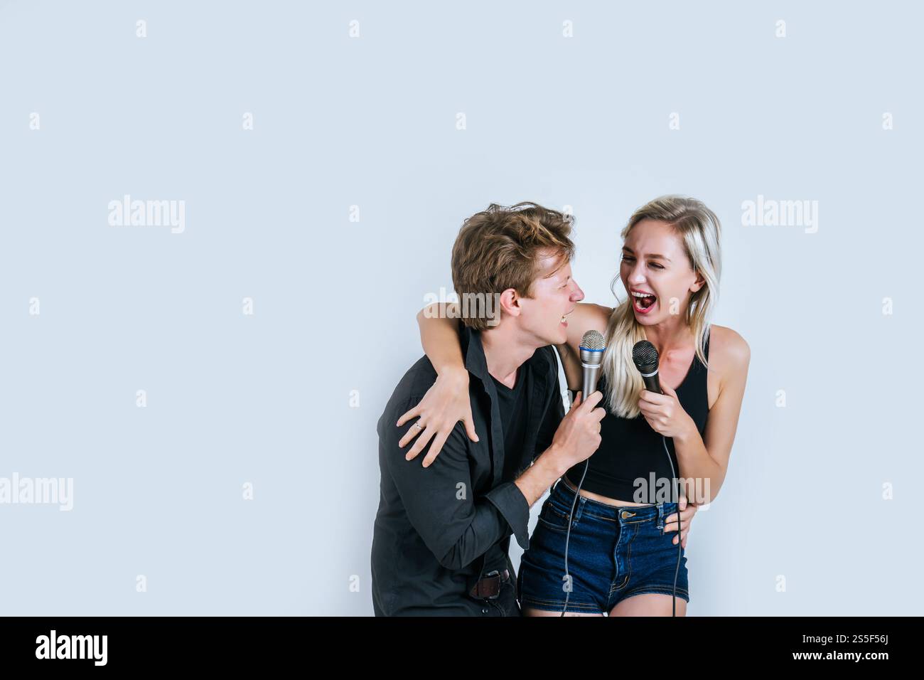 Felice ritratto di coppia tenendo il microfono e cantando una canzone Foto Stock