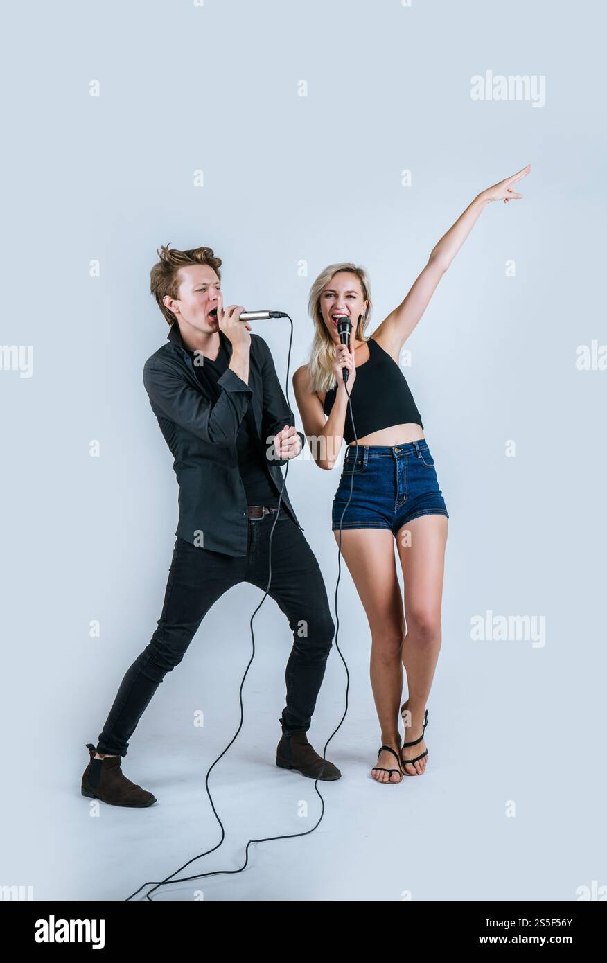 Felice ritratto di coppia tenendo il microfono e cantando una canzone Foto Stock
