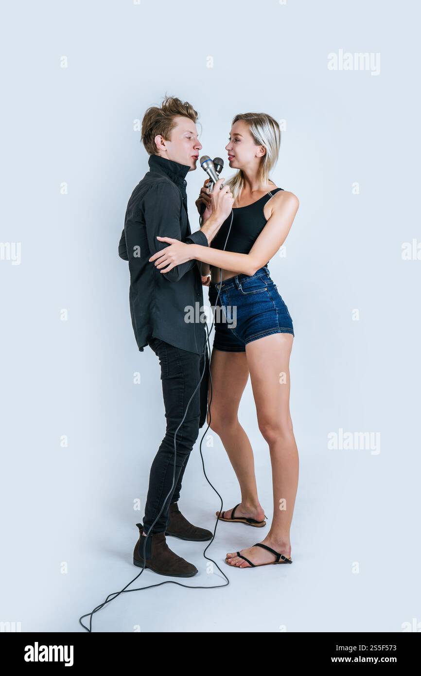 Felice ritratto di coppia tenendo il microfono e cantando una canzone Foto Stock