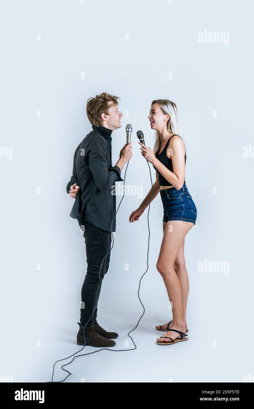 Felice ritratto di coppia tenendo il microfono e cantando una canzone Foto Stock