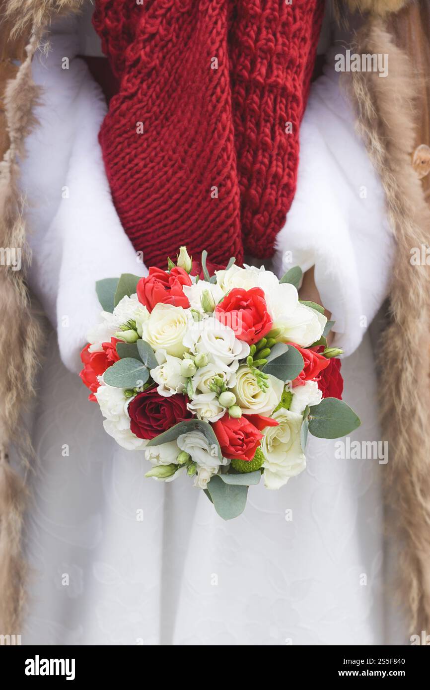 Bouquet di nozze invernale tra le mani della sposa in una giornata nevosa Foto Stock