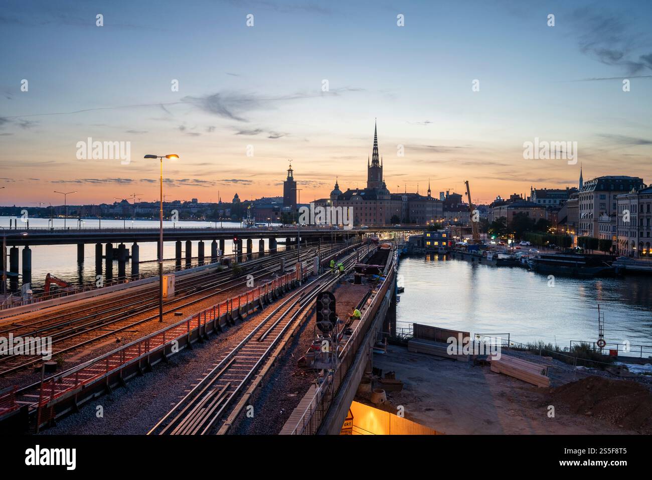 Tramonto sulla città di Stoccolma con una vista dei binari ferroviari, del cantiere e dello skyline storico di Gamla Stan, la città vecchia di Stoccolma Foto Stock