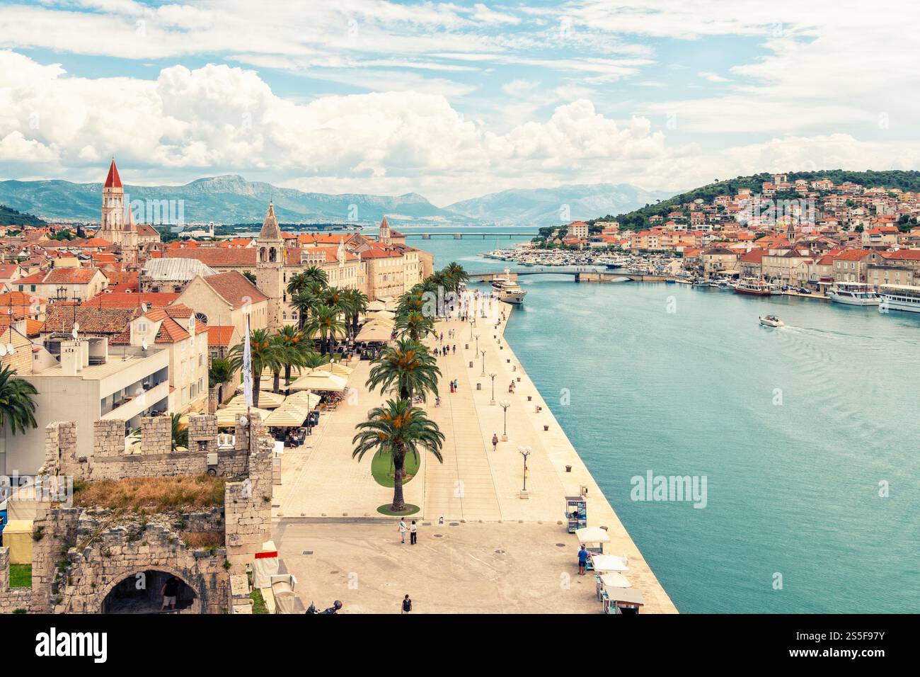 Vista aerea di una città costiera mediterranea di Traù con architettura storica lungo un mare Adriatico azzurro e cristallino sotto un cielo parzialmente nuvoloso, la Croazia Foto Stock