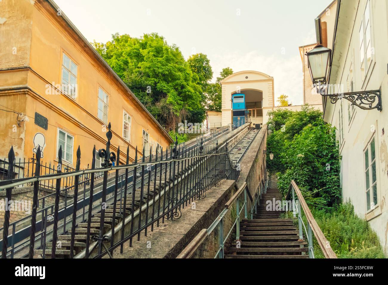 Scala e funicolare di Zagabria che conducono ad un edificio classico con un cielo blu e lussureggianti alberi verdi sullo sfondo, Zageb, Croazia Foto Stock