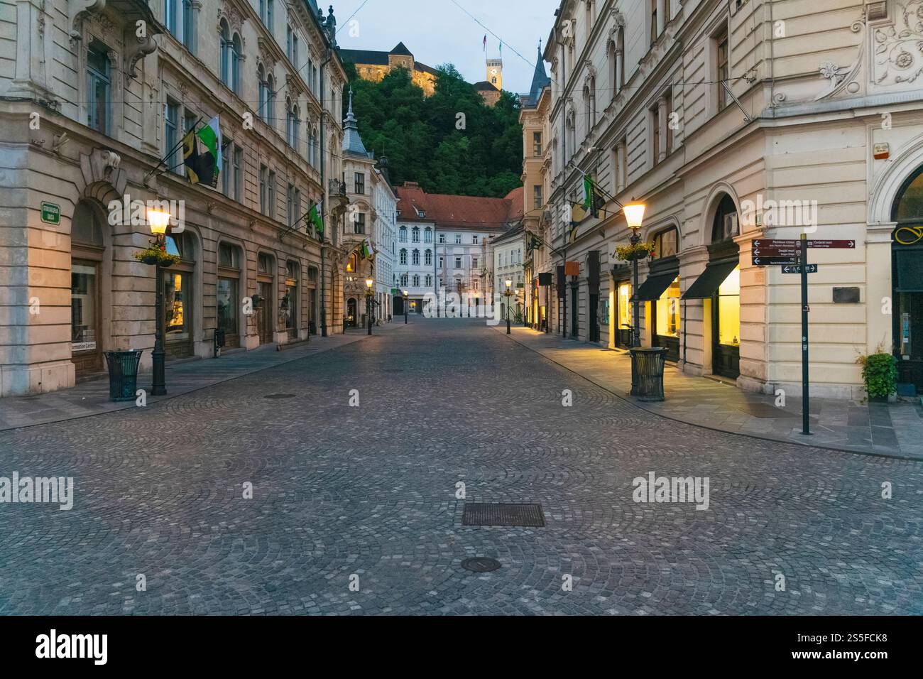 Via ciottoli vuota al crepuscolo con architettura europea e un castello di Lubiana in cima alla collina sullo sfondo, Lubiana, Slovenia Foto Stock