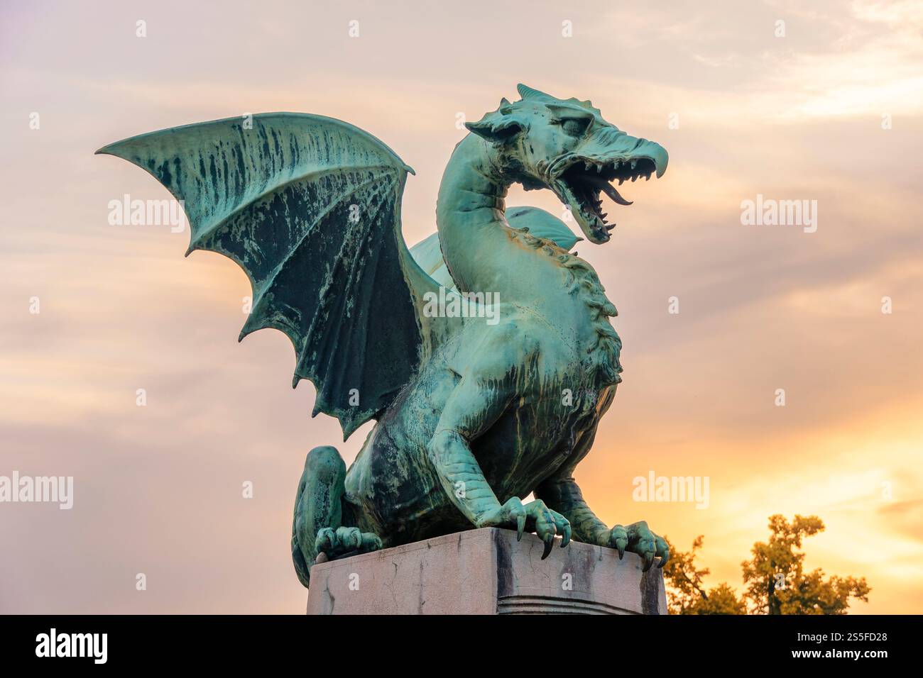 Una statua di drago verde con ali allungate contro un cielo crepuscolo sul Ponte del Drago a Lubiana, Slovenia Foto Stock