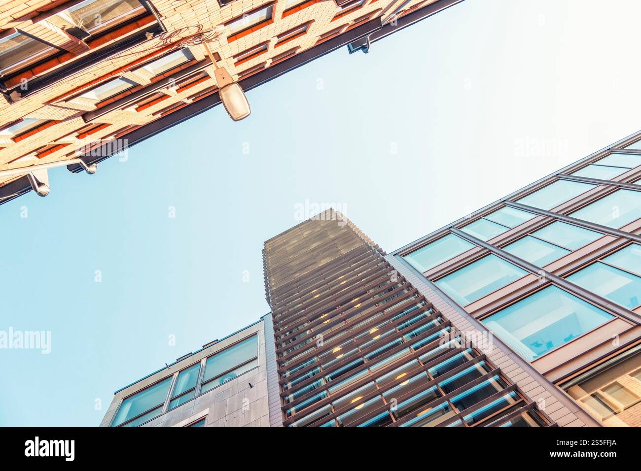 Vista verso l'alto dei moderni e alti edifici contro un cielo blu limpido con un lampione visibile nel centro di Stoccolma, Svezia Foto Stock