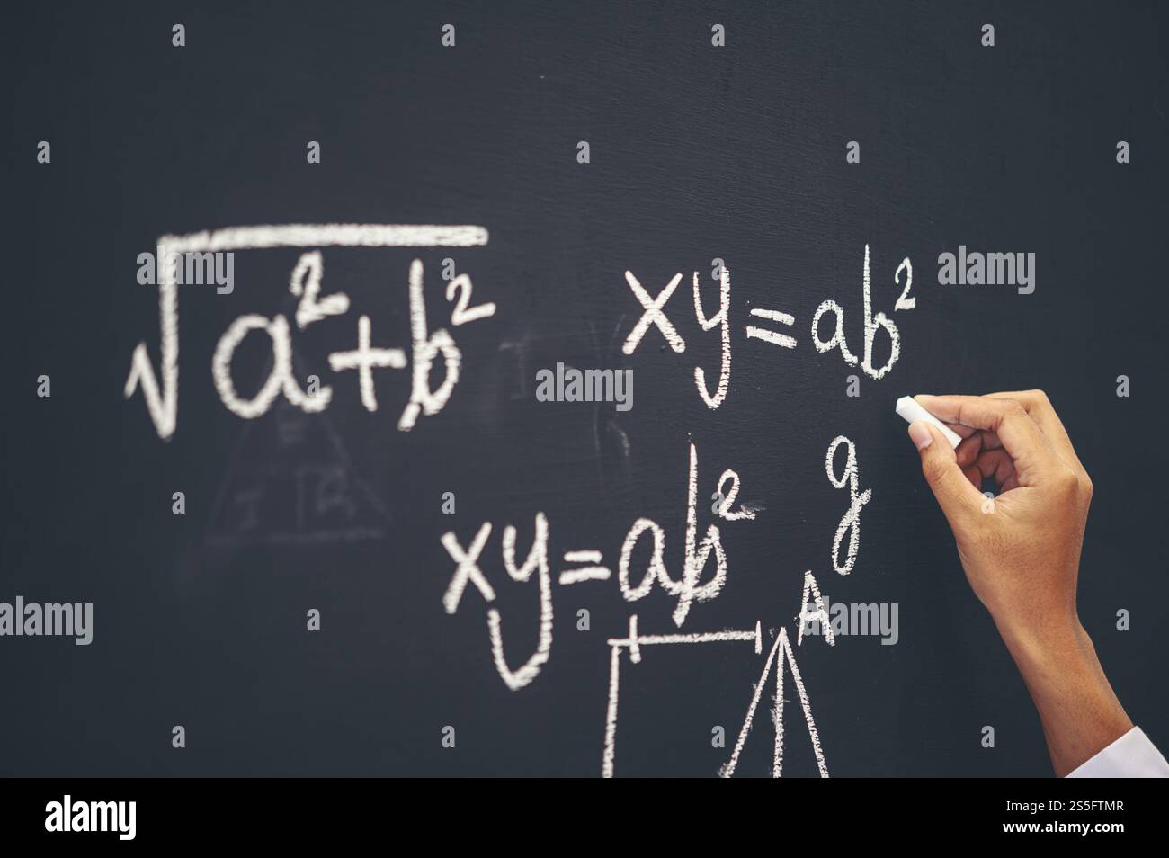 La mano che scrive la formula con gesso bianco sulla lavagna Foto Stock