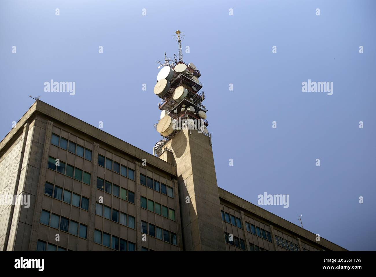 Torre di comunicazione con più antenne sulla sommità di un edificio in cemento contro un cielo azzurro, Teheran, Iran Foto Stock