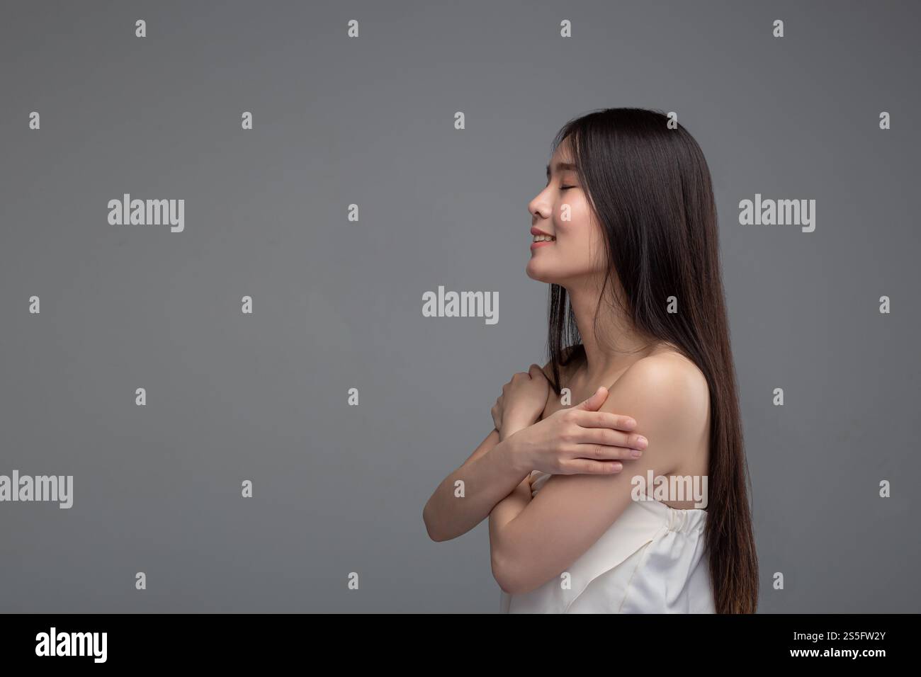 La donna indossa una camicia senza spalline che sta con le braccia incrociate, presa dal lato sinistro Foto Stock