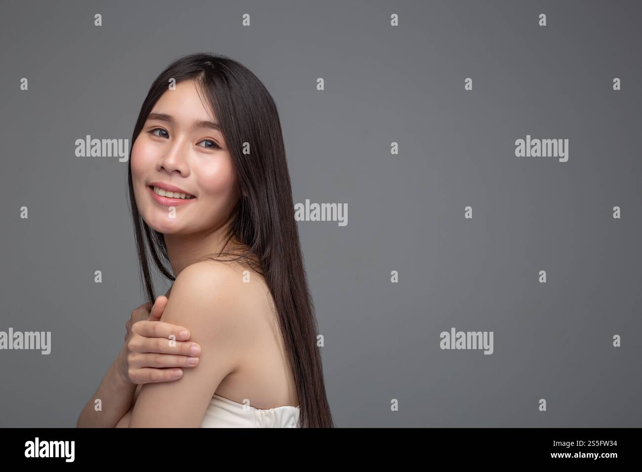 La donna indossa una camicia senza spalline che sta con le braccia incrociate, presa dal lato sinistro Foto Stock