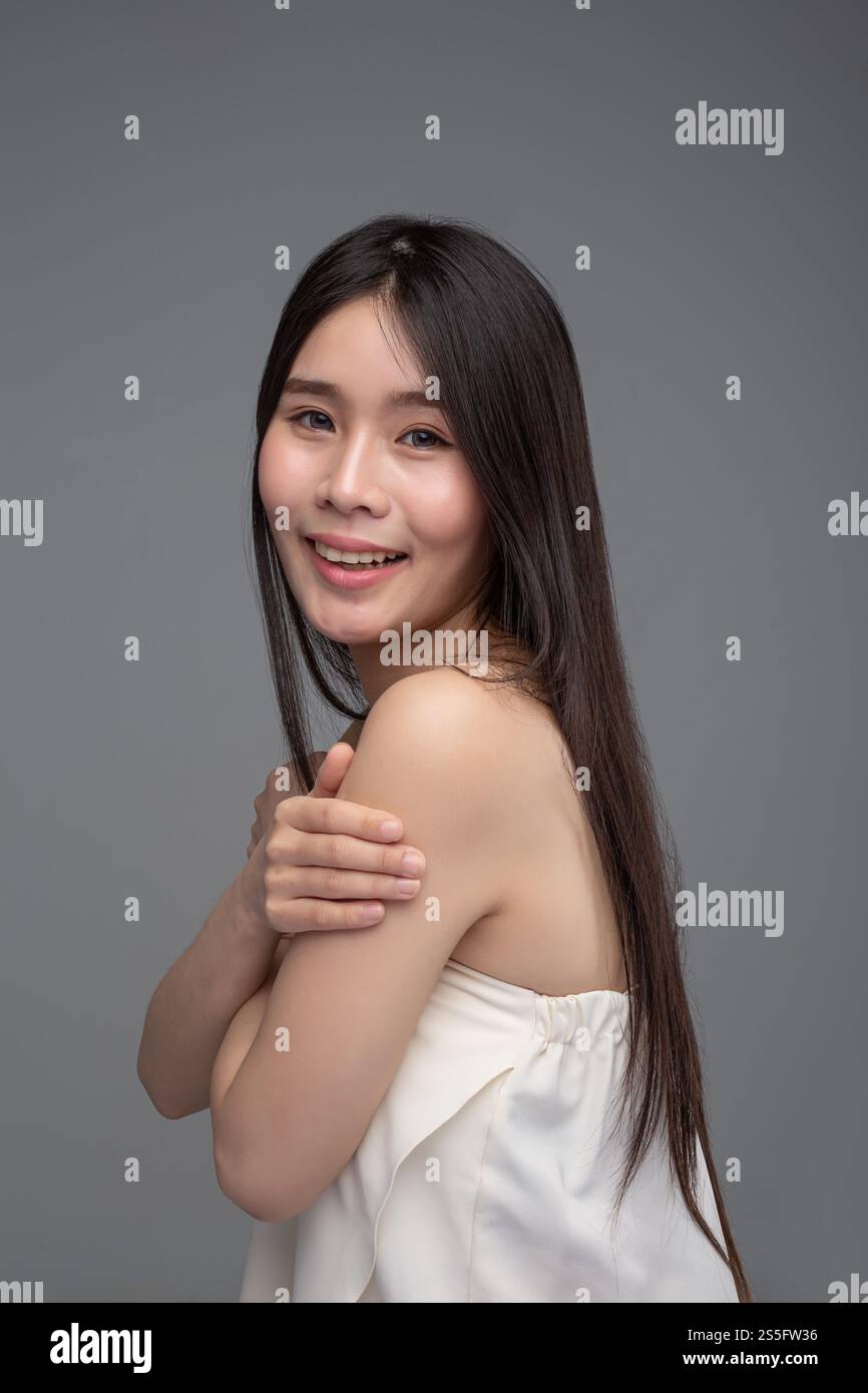 La donna indossa una camicia senza spalline che sta con le braccia incrociate, presa dal lato sinistro Foto Stock