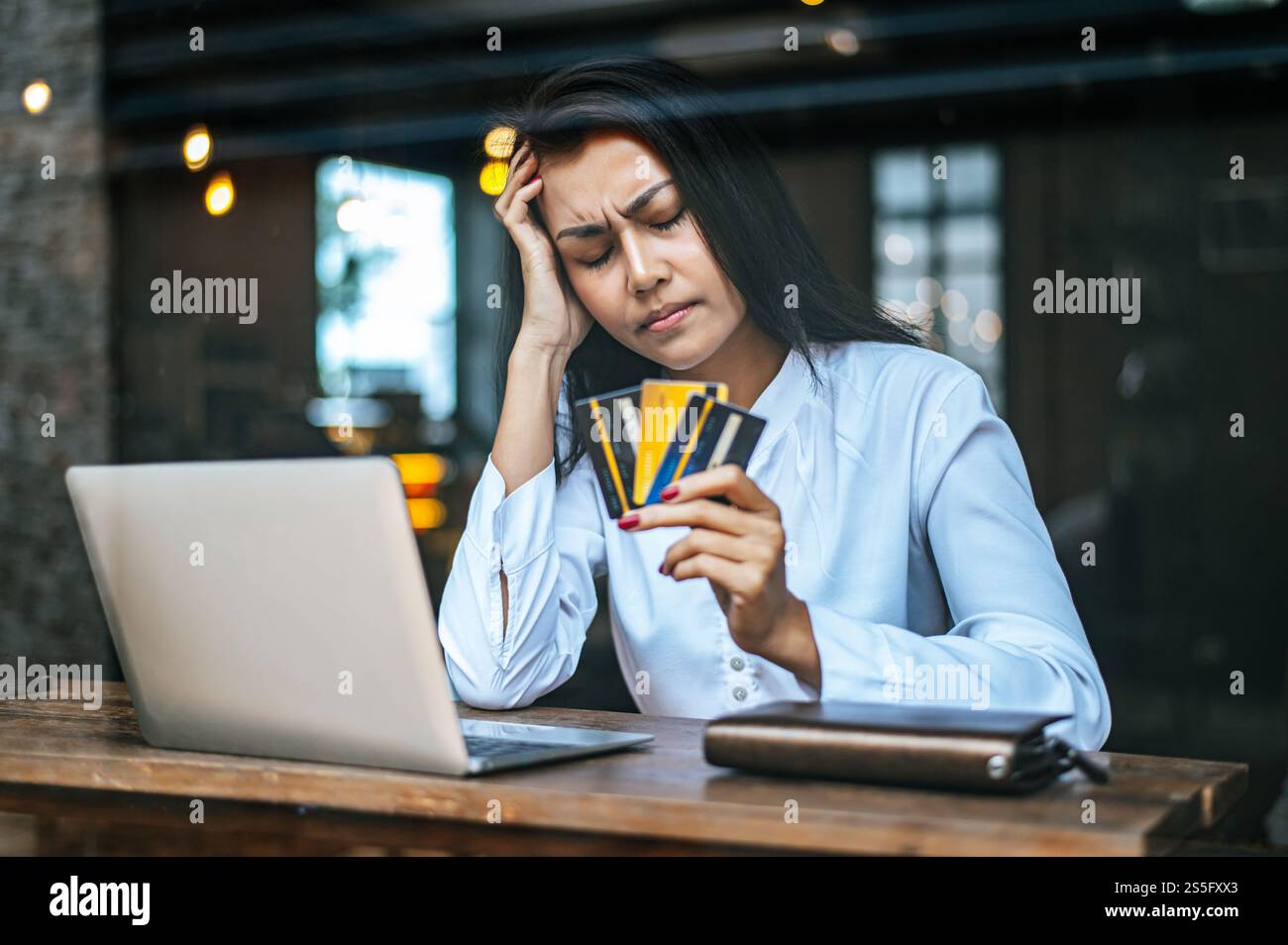 donna seduta a pensare ai saldi delle carte di credito, notebook. Foto Stock