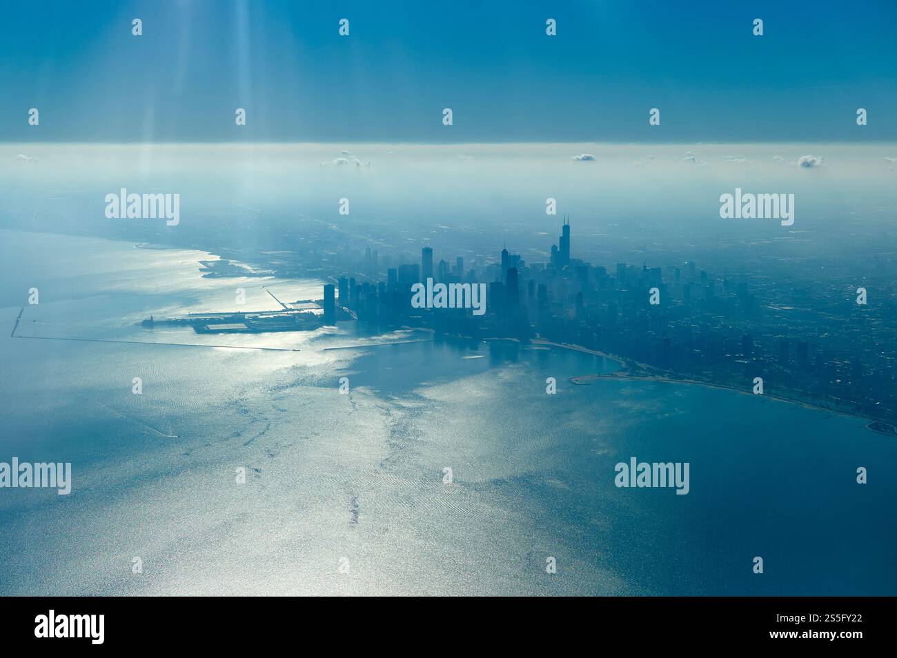 Vista aerea dello skyline della città sullo sfondo di un vasto corpo d'acqua illuminato dal sole sotto un cielo azzurro, New Orleans, Stati Uniti Foto Stock