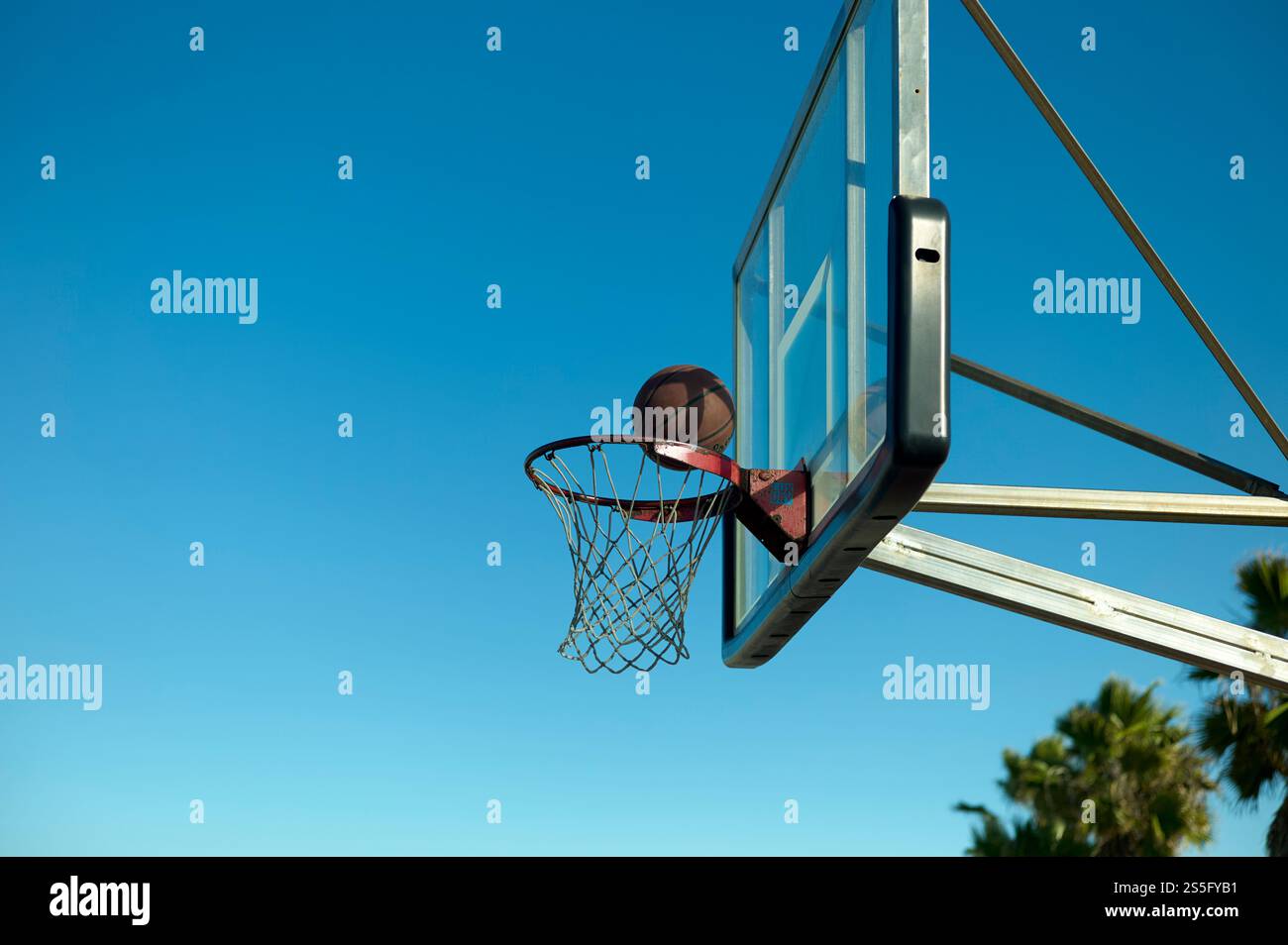Un pallacanestro che segna un gol attraverso un cerchio contro un cielo azzurro limpido, New Orleans, USA Foto Stock
