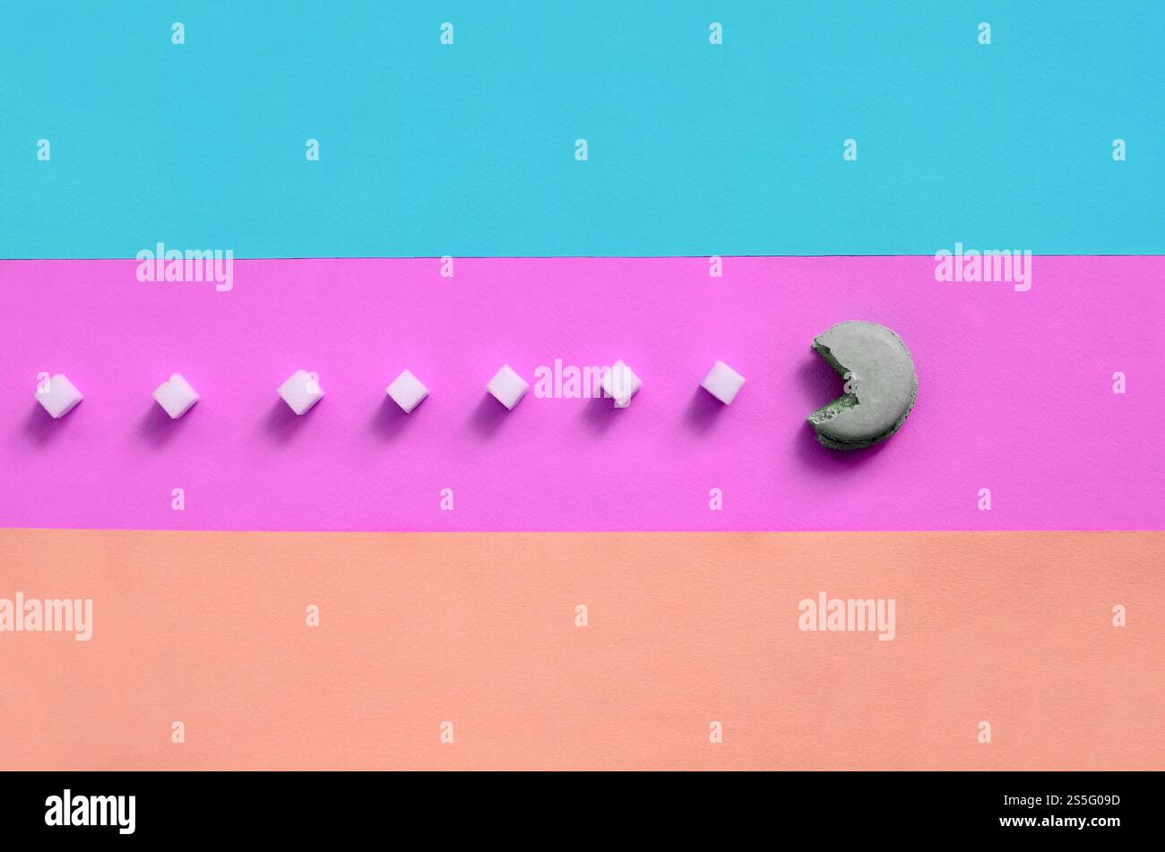 Una composizione di macaroon a bocca aperta che mangia cubetti di zucchero su sfondo rosa, lime, blu e corallo pastello. Il concetto di vecchio Foto Stock