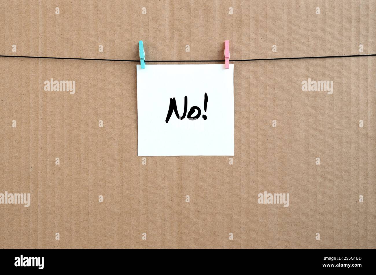 No! La nota è scritta su un adesivo bianco appeso a un clothespin su una corda su uno sfondo di cartone marrone Foto Stock