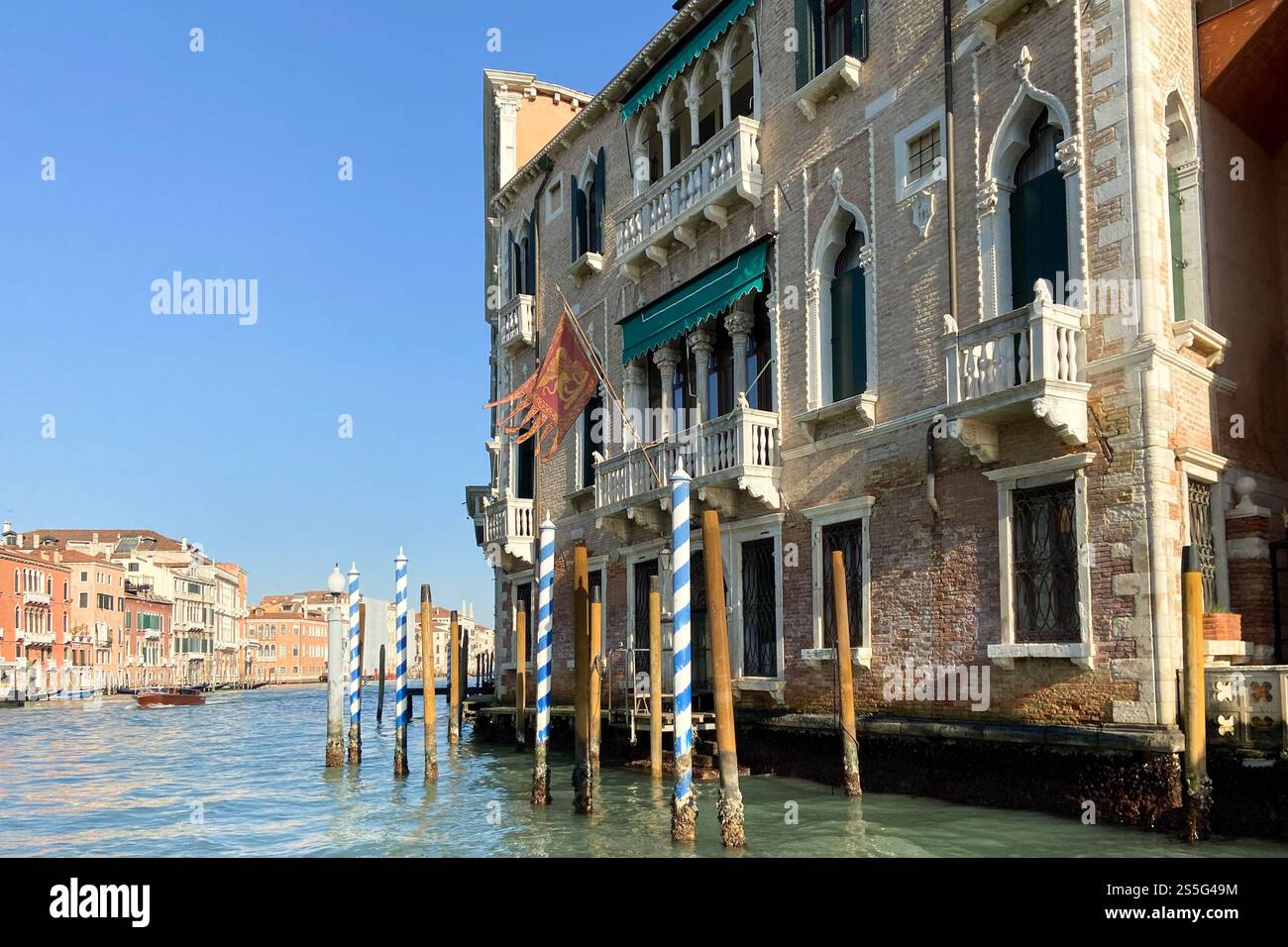 Vista della casa con bandiera veneziana sul lungomare del Canal Grande da vaporetto a Venezia città nel mese di febbraio morming Foto Stock