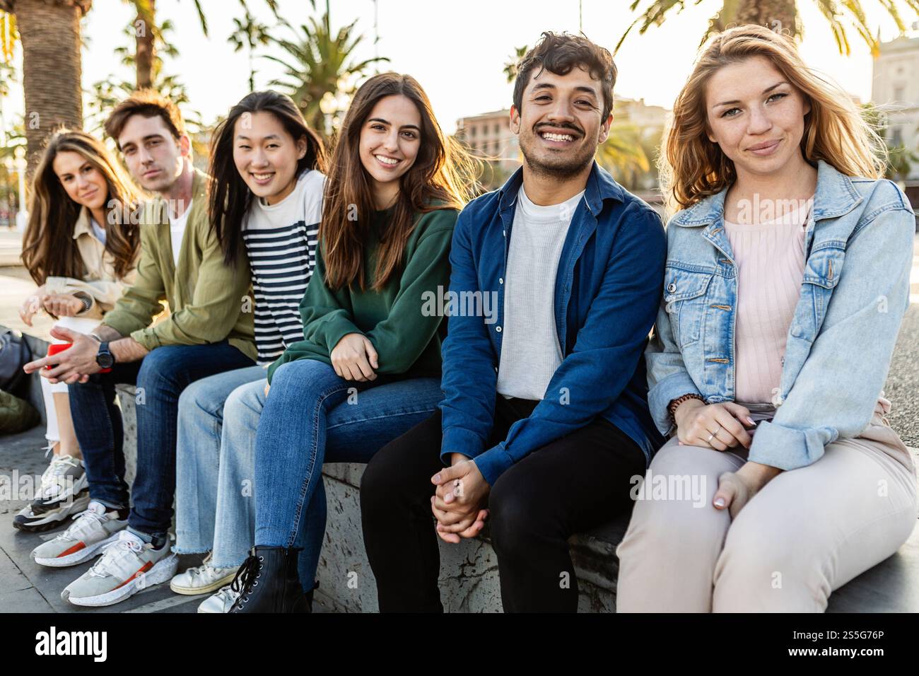 Felici amici multietnici seduti insieme all'aperto in città Foto Stock