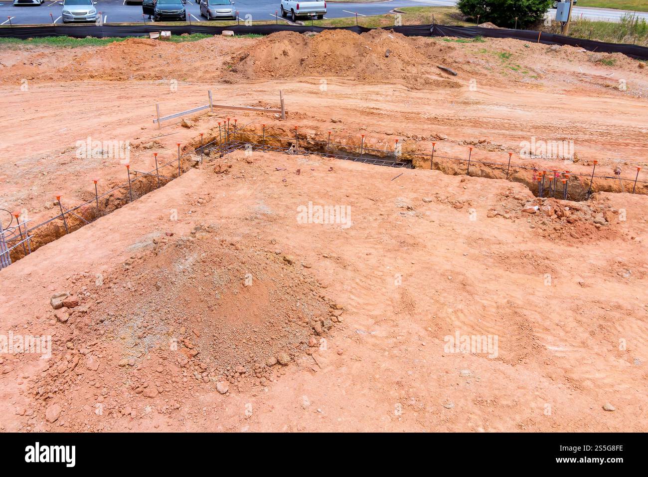 Macchinari pesanti scavano, preparano il terreno per una nuova struttura nel quartiere in via di sviluppo con auto parcheggiate. Foto Stock