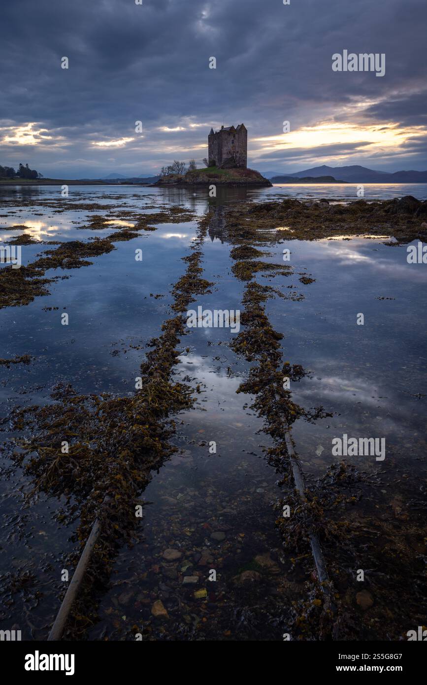 Le tracce conducono allo storico castello scozzese di Castle Stalker al tramonto. Castle Stalker si trova nel lago di Loch Laich, parte di Loch Linnhe, ON Foto Stock
