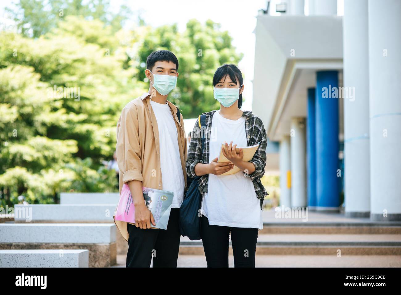 Gli studenti di sesso maschile e femminile indossano una maschera di salute e parlano tra loro sulle scale. Foto Stock