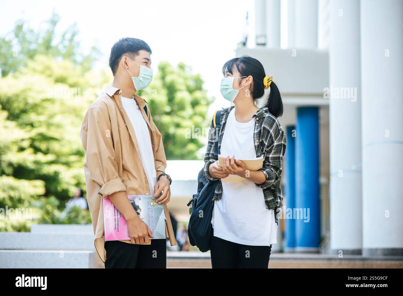 Gli studenti di sesso maschile e femminile indossano una maschera di salute e parlano tra loro sulle scale. Foto Stock