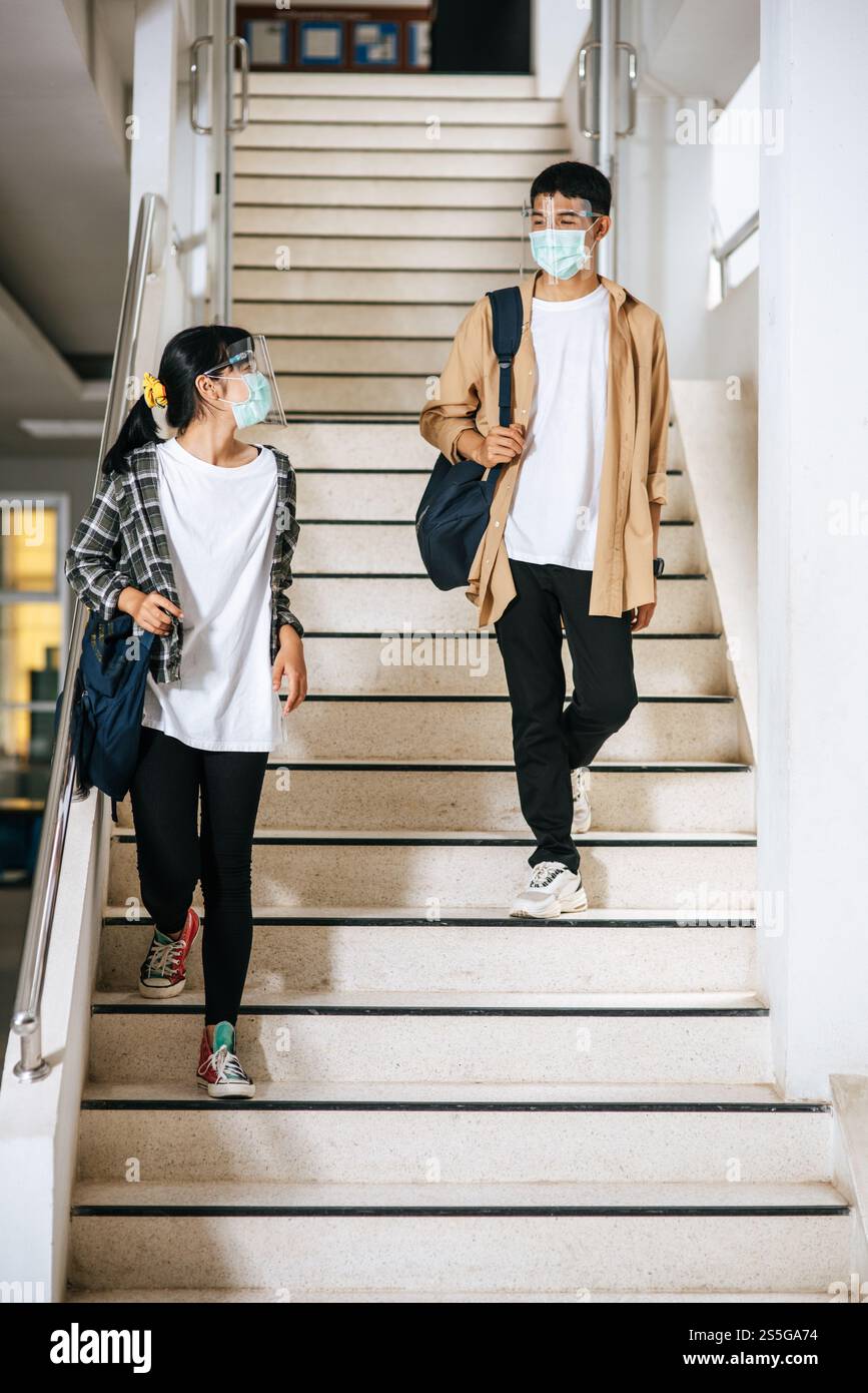 Gli studenti di sesso maschile e femminile indossano una maschera di salute e parlano tra loro sulle scale. Foto Stock