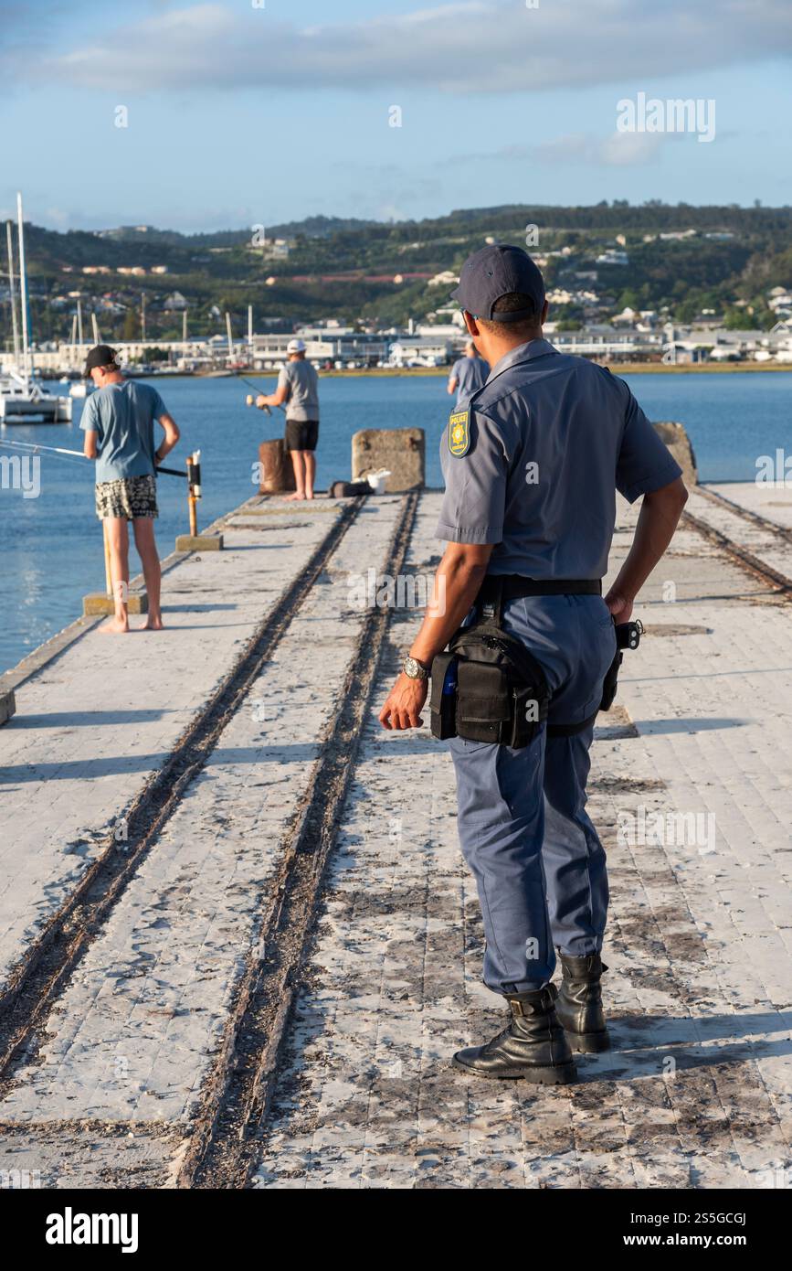 Knysna, Capo Occidentale, Sudafrica. 08.12.2024. Ufficiale di polizia in forma non forme e con una pistola in una fondina sul lungomare di Knysna. Foto Stock