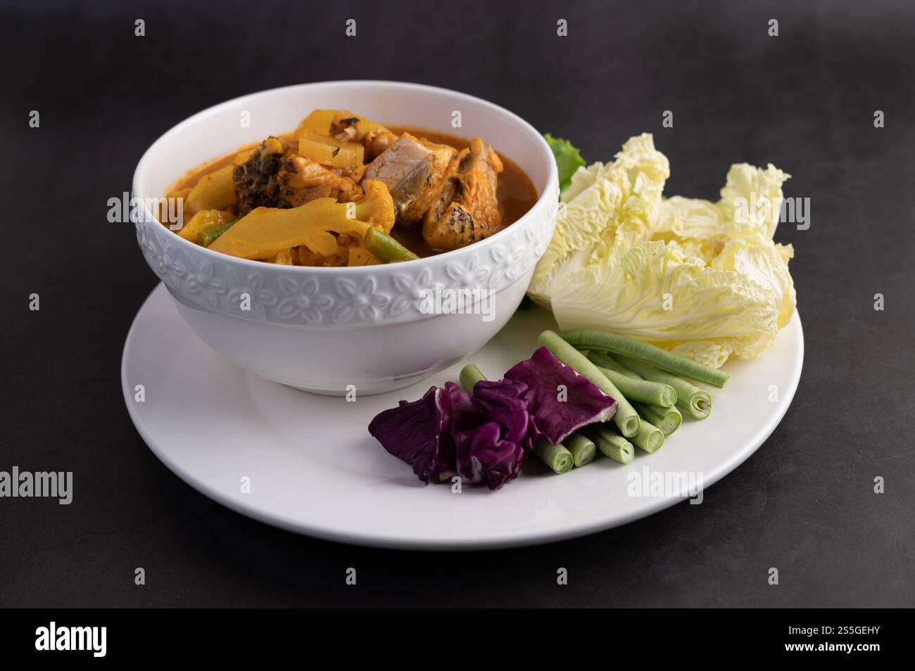 Curry giallo con pesce testa di serpente, cibo tailandese in una ciotola su un piatto con fagioli lunghi, cavolo bianco fritto, insalata e cavolo viola Foto Stock