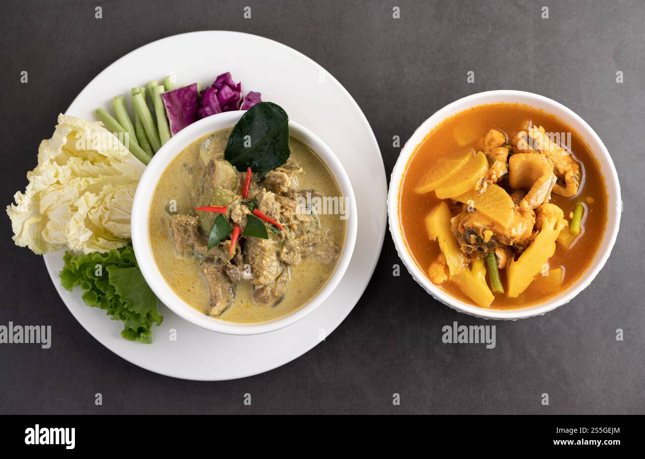 Pollo al curry verde in una tazza bianca e pesce al curry Snakehead sul terreno di cemento Foto Stock