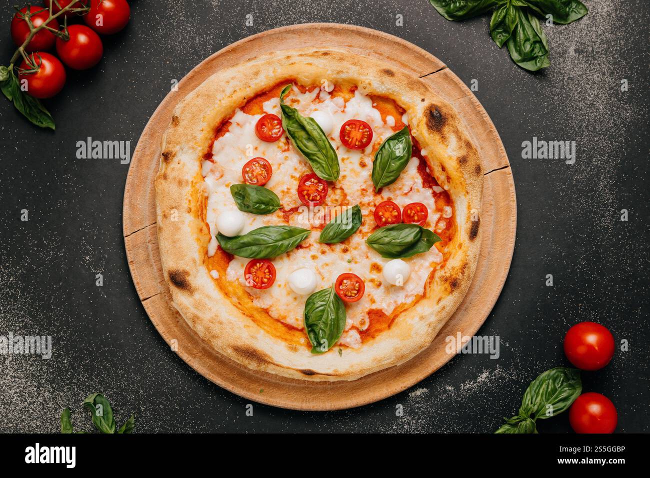 Pizza Margherita con basilico fresco, mozzarella e pomodori ciliegini su un piatto rustico di legno Foto Stock