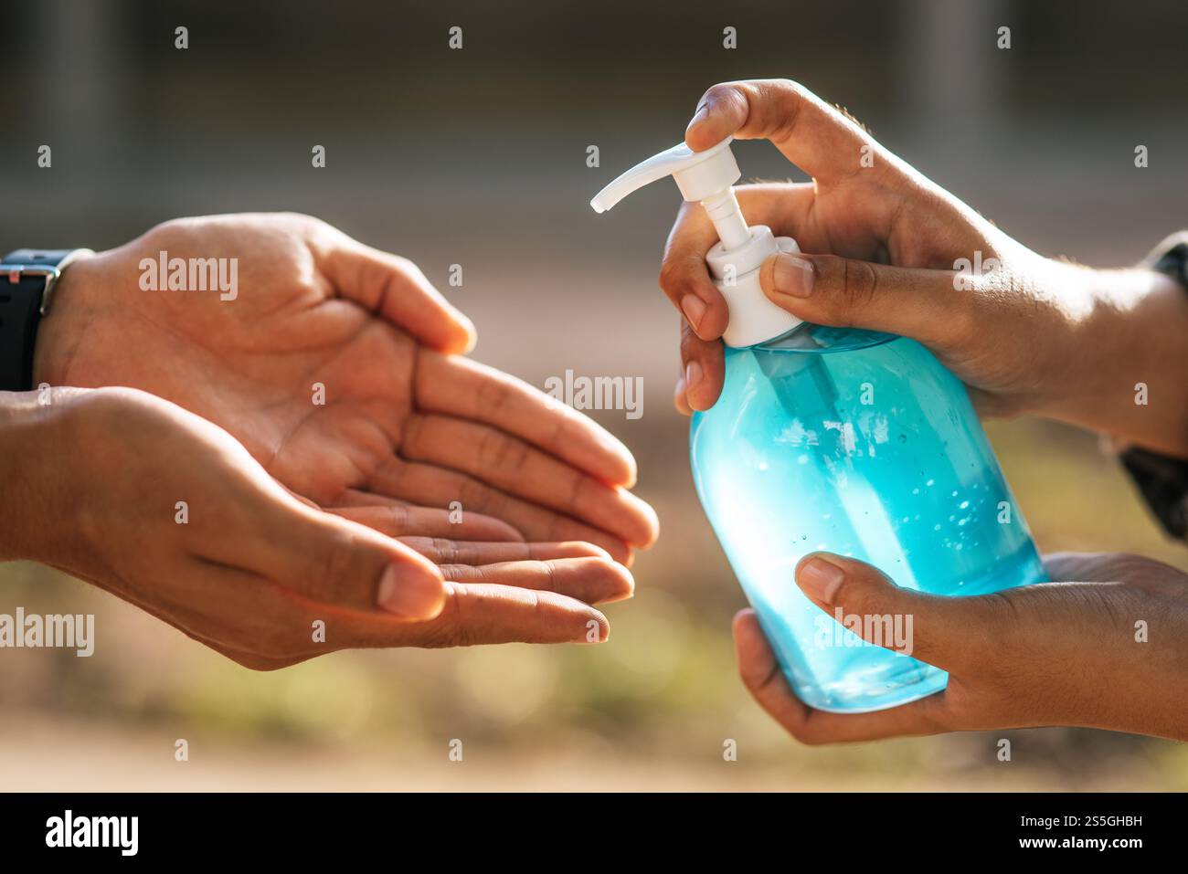 Mani in corrispondenza del flacone di gel per lavarsi le mani e stringere per consentire agli altri di lavarsi le mani. Foto Stock