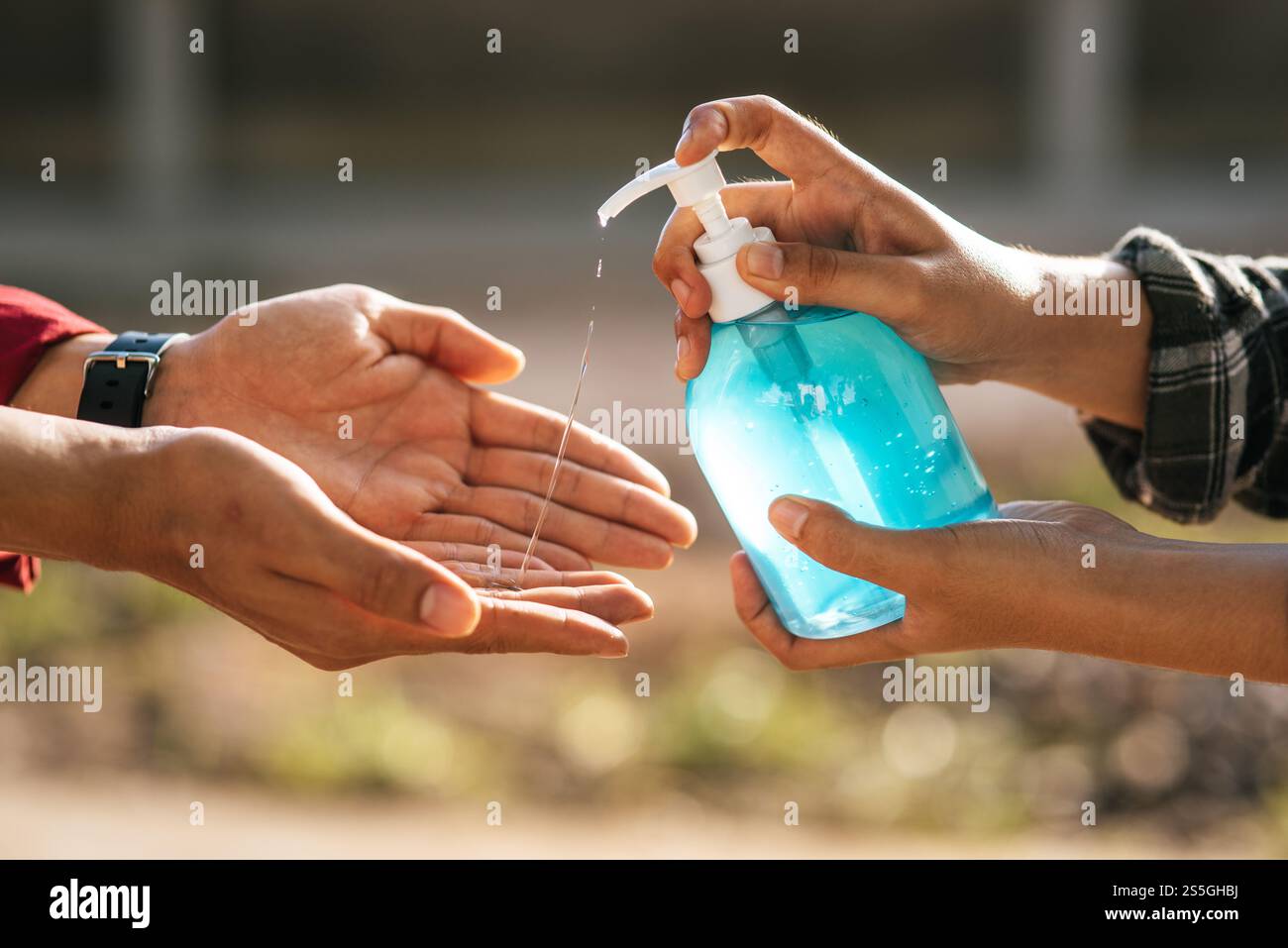 Mani in corrispondenza del flacone di gel per lavarsi le mani e stringere per consentire agli altri di lavarsi le mani. Foto Stock