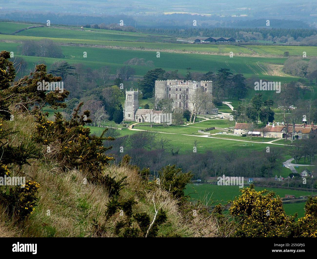 Il castello di Lulworth del XVII secolo con la chiesa di Sant'Andrea del XV secolo nei suoi giardini. Preso in una luminosa giornata primaverile dalle colline sopra coperte Foto Stock