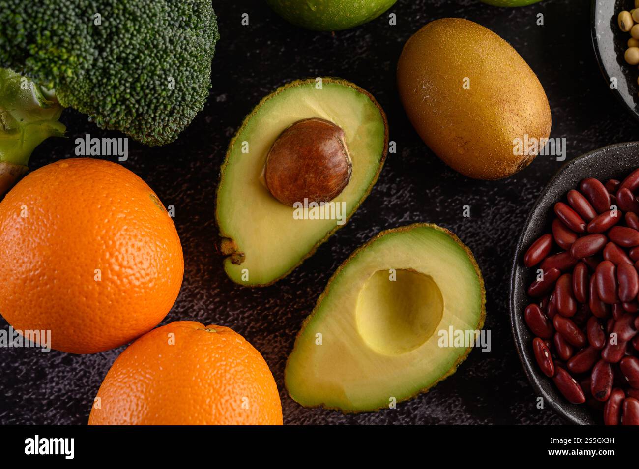 Broccoli, arancia, kiwi, avocado e fagioli rossi su fondo in cemento nero. Foto Stock