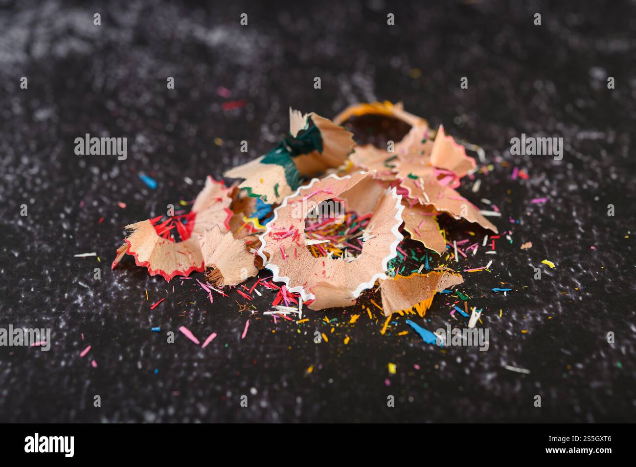 Primo piano con rasature a matita di legno disposte su pavimenti in cemento nero. Foto Stock